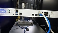 Perangkat firewall Sophos XGS terpasang di rak server dengan kabel jaringan biru dan putih.