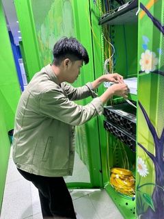 Anggota tim memasang kabel pada perangkat jaringan di dalam rak server.